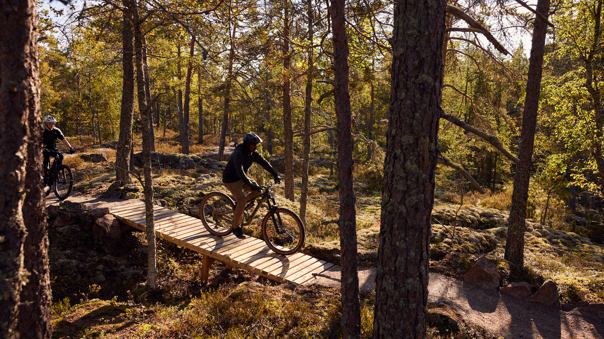 Bild på två personer som cyklar i skogen i Södra Berget Bike Arena